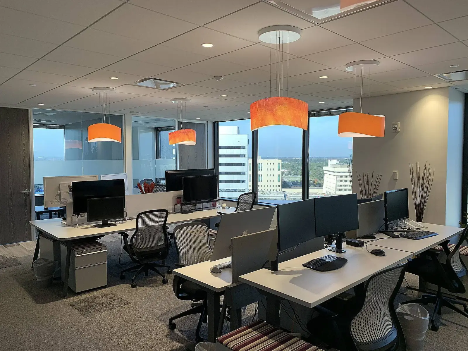 Open workstations and orange pendant lights in the BidZone Orlando office